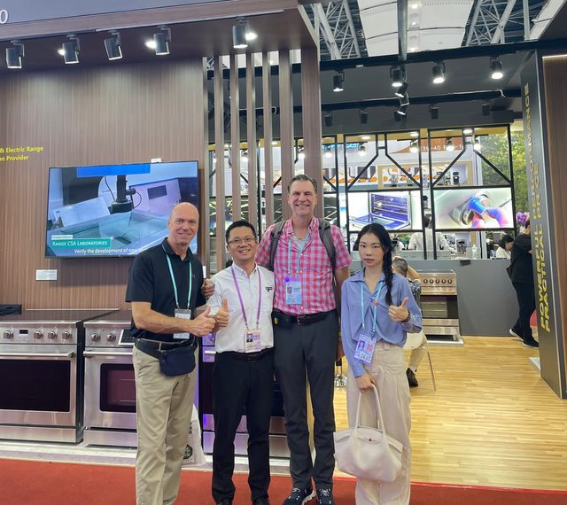 Shirley Chou with two overseas buyers and a supplier at a cooking range stand at a Guangzhou trade exhibition