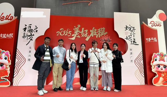 Shirley Chou and a group of visiting clients in front of a red Chinese New Year 2025 display