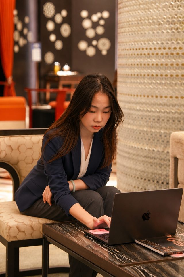 Shirley Chou in a navy blazer reaching over a laptop in a hotel lounge
